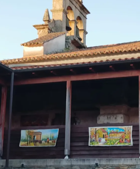Espadaña de piedra, campanas y balconada de madera con tapices en San Salvador de Bergondo